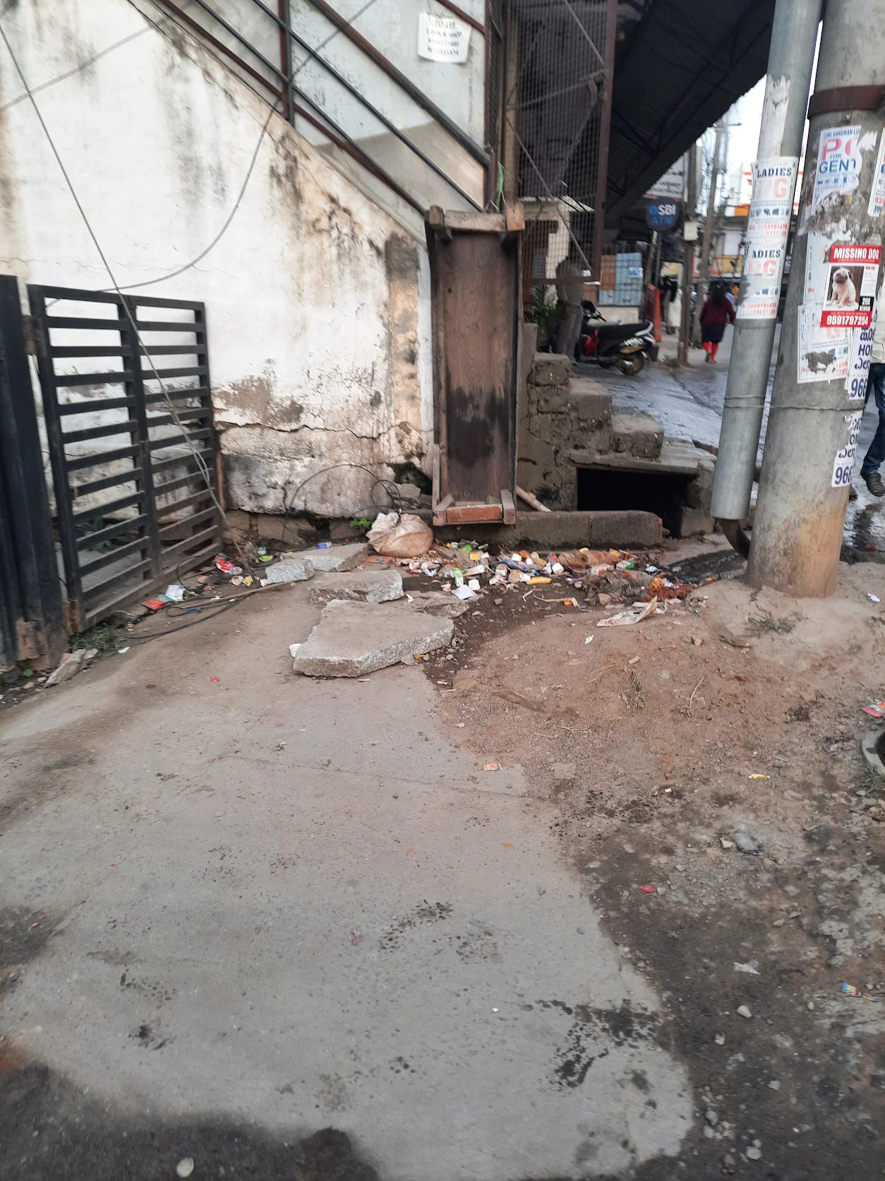 Open gutter and scattered waste at the back gate of a HustleHub building